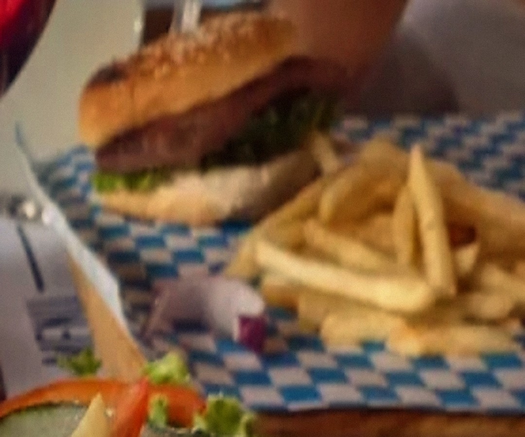 Hamburguesa de la casa con papas a la francesa servida sobre papel a cuadros